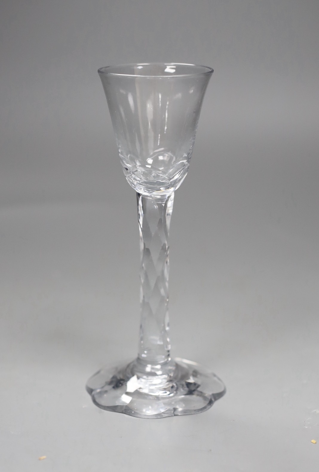An 18th century facet stemmed glass with a petal foot, 16.5 cms high